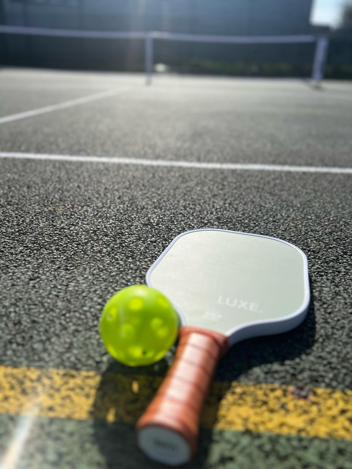 Pickleball paddle and ball on court
