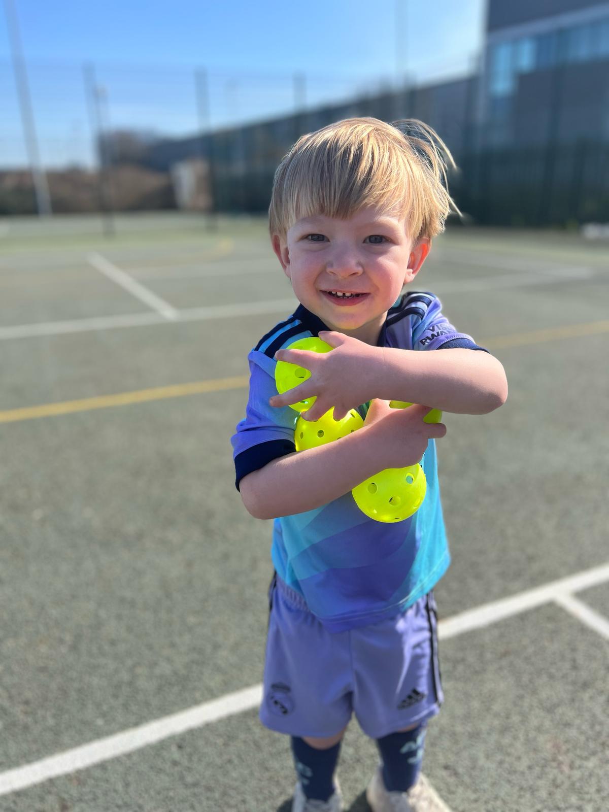 Child holding pickleball balls