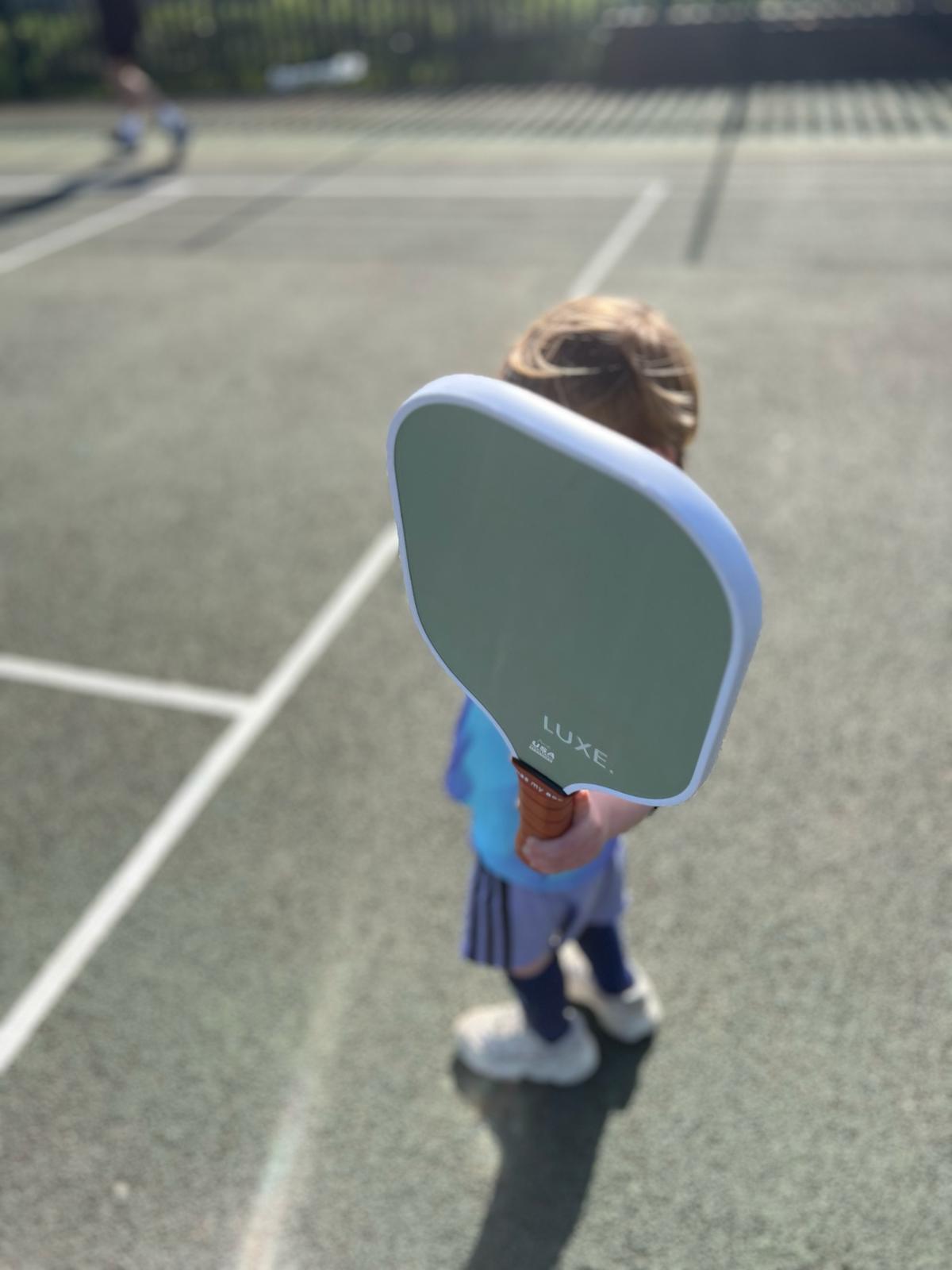 Child holding pickleball paddle
