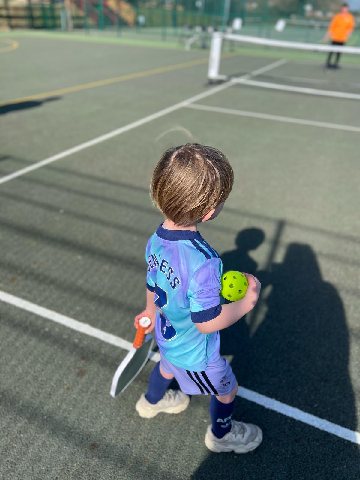 Child playing pickleball on court